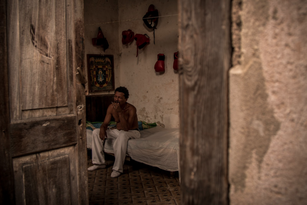 Boxer in Cuba shot through a doorway sitting on a bed