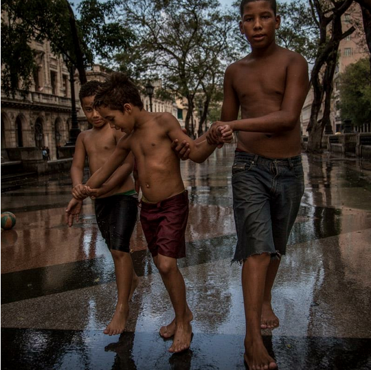 Cuba young boys playing in a square after rain