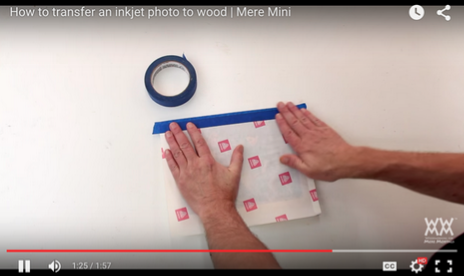 A paused YouTube clip of a person taping a piece of paper to a surface