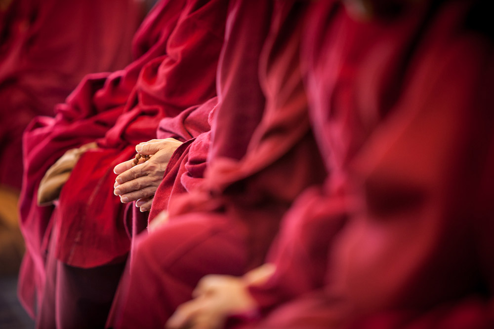 monks in red robes praying.