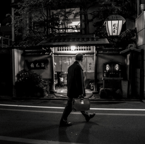 black and white photo of a man in old town kyoto walking
