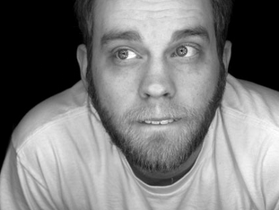 black and white photo of a male presenting person wearing a white t-shirt and lit by a continuous ring light