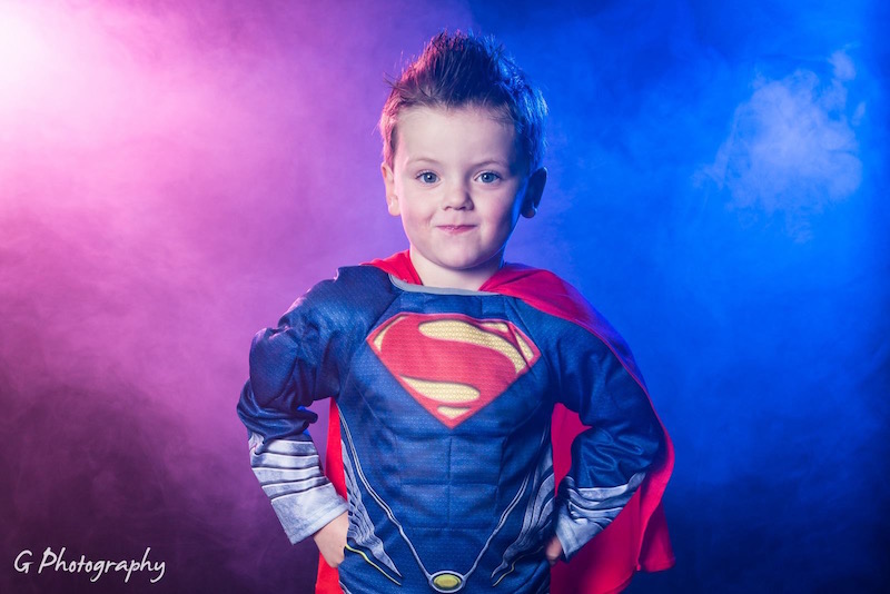 colour gel background little kid dressed as Superman with colour gel background