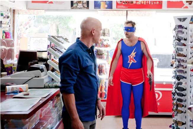 heavily backlit shot of two men in a convenience store on in a super hero outfit