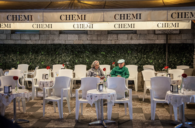 older couple sitting at a table surrounded by empty tables in Sicily 