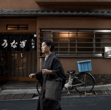 A woman walking down a street in front of an older style Japanese building
