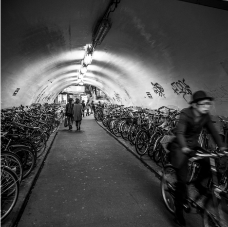 black and white photo of an underground pass in japan lined with parked bicycles