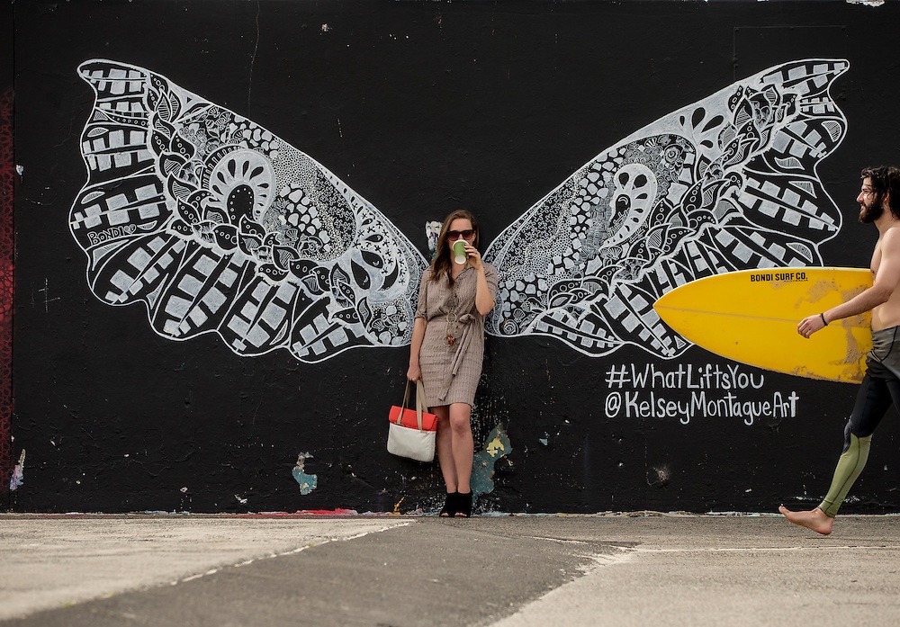 woman in front of butterfly wing mural